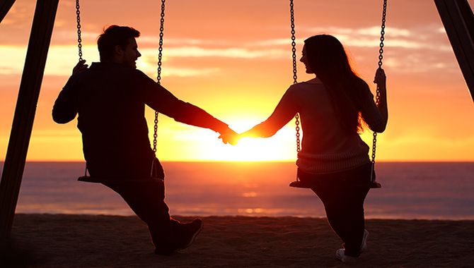 Couple silhouette holding hands watching a sunrise